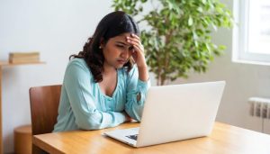 Woman sitting in front of laptop in serious mood digital arrest Depositphotos_769832686_XL (1) (1)